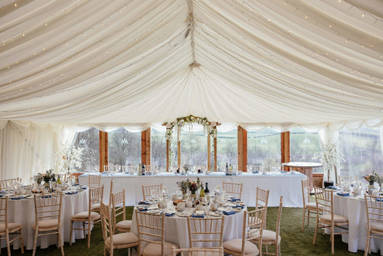 Room for wedding meal set up with draped ceilings and fairy lights